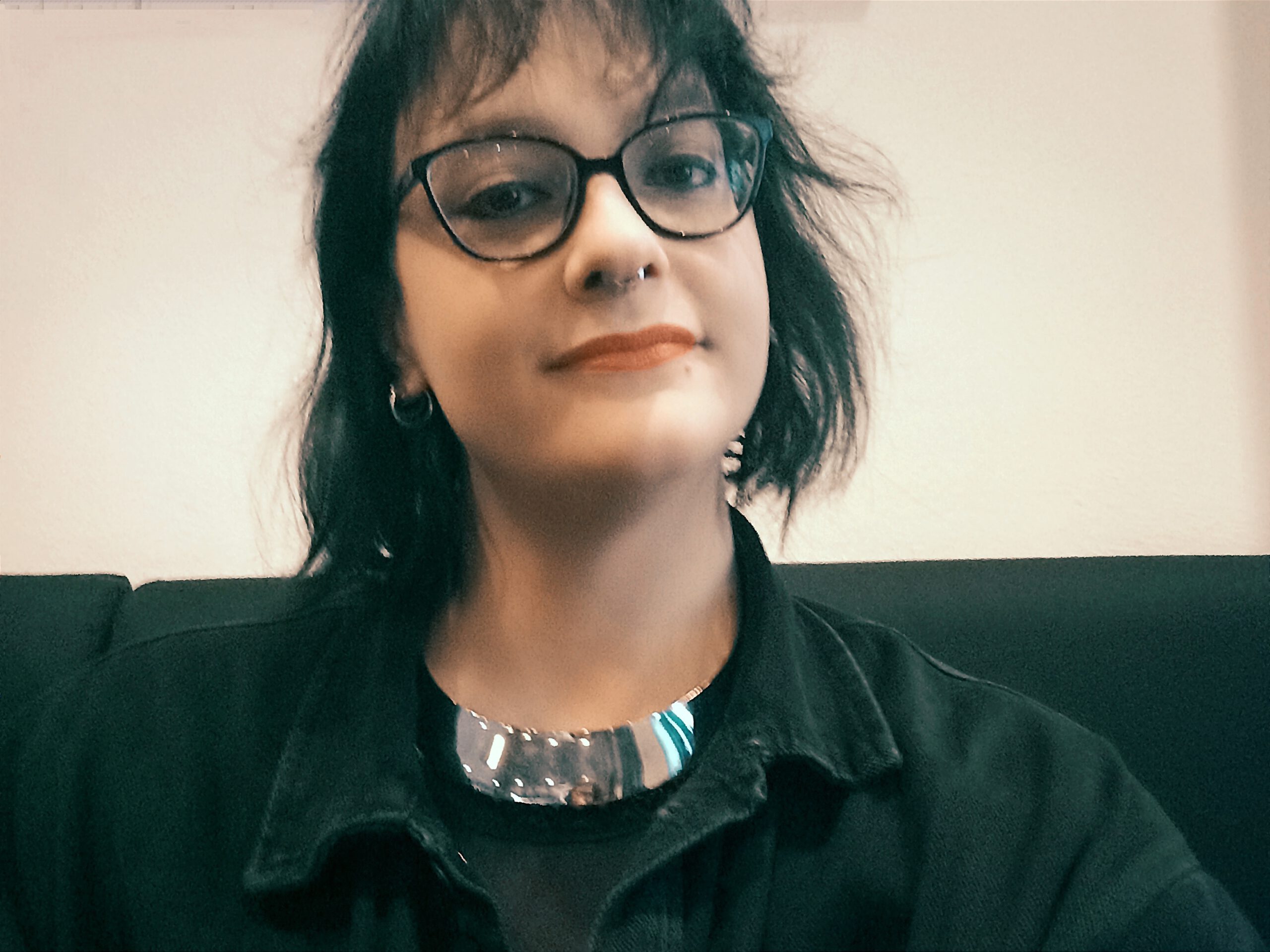 Porträt von Paula Balov, einer Frau mit Brille und schwarzem Shirt, die direkt in die Kamera blickt.